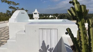 A white building with a tower, a cactus, and a clear sky.