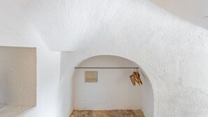 A room with a white textured ceiling, an arched doorway, and a stone floor. - Trulletto Lavanda by Rentbeat (Ceglie Messapica)