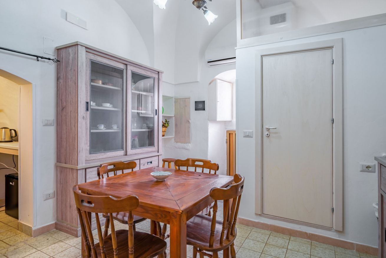 A dining area with a wooden table and chairs, a cabinet with glass doors, and a white door.