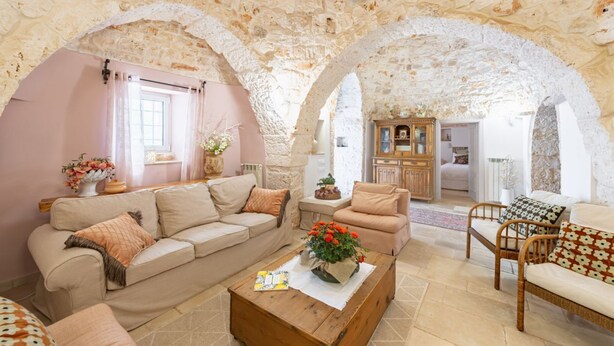 A cozy living room with a stone ceiling, a wooden coffee table, and a sofa. - Trulli Garden Harmony by Rentbeat (Martina Franca)