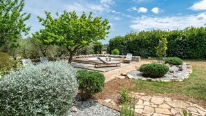 A garden with a hot tub, seating area, and stone pathways.