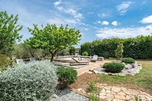 A garden with a hot tub, seating area, and stone pathways.