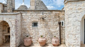 A stone building with a small window, three terracotta pots, and a stone archway.