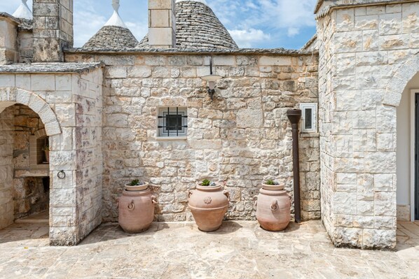 A stone building with a small window, three terracotta pots, and a stone archway.