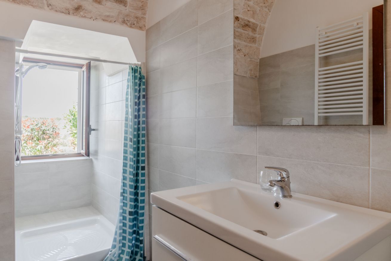 Un baño con ducha, lavamanos y espejo.