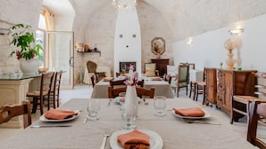 A dining area with tables set for four, a chandelier, and a fireplace. - Masseria Carbonico delle Lamie by Rentbeat (Martina Franca)