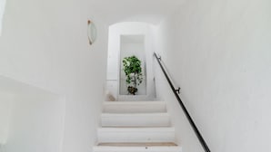A white staircase with a handrail, leading to a doorway with a plant. - Masseria Carbonico delle Lamie by Rentbeat (Martina Franca)