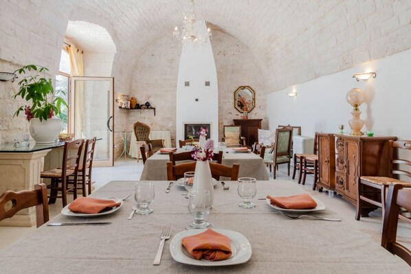 Un comedor con mesas dispuestas para cuatro, una araña y una chimenea.