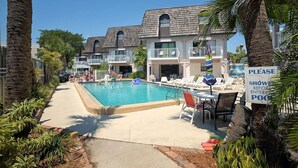 A pool area with lounge chairs and a sign instructing to shower before entering the pool.