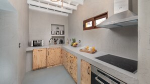 A modern kitchen with a built-in oven, microwave, and a large stove. There is a wooden cabinet and a small window above the stove.
