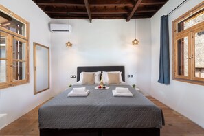 A bedroom with a bed, two bedside lamps, a window, and an air conditioning unit.