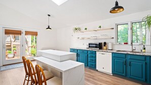 A modern kitchen with teal cabinets, a white countertop, and a black pendant light. - Scarborough Sanctuary-Cozy retreat close to all local attractions. (Scarborough)