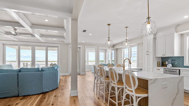 Cocina amplia con isla central, muebles blancos y vistas al exterior.