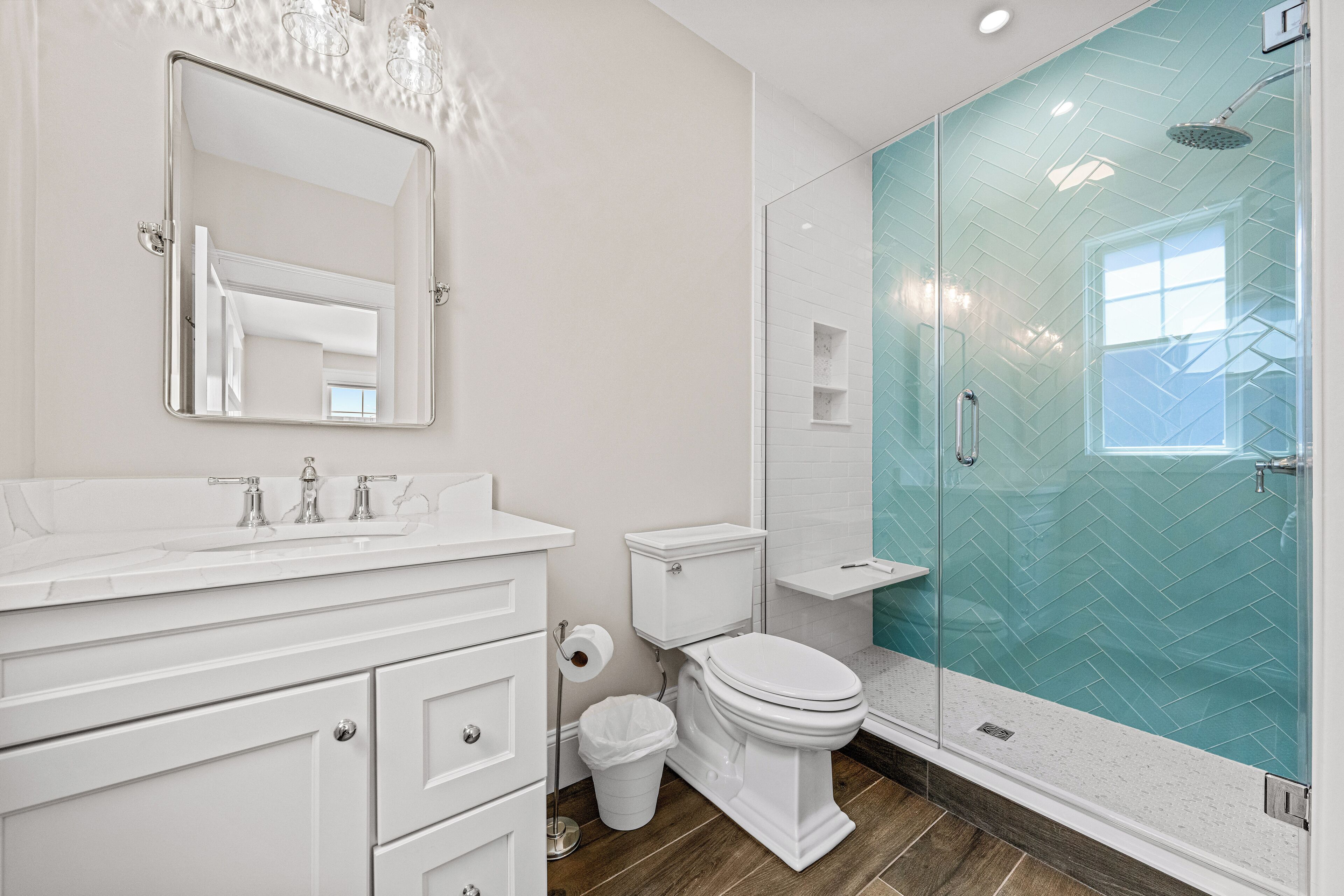 A modern bathroom with a white vanity, a toilet, and a glass-enclosed shower.
