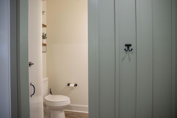 A bathroom with a toilet, a shower, and a towel rack.