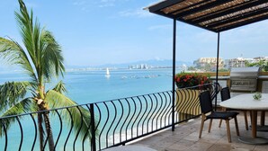 Eine Terrasse mit Meerblick, inklusive Grill, Sitzgelegenheit und einem kleinen Tisch.