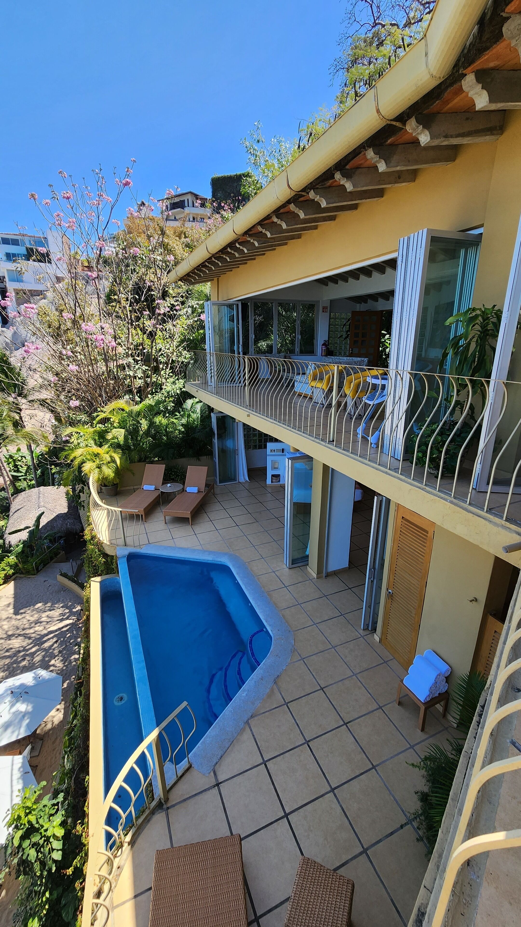 A pool area with a sun terrace, lounge chairs, and a covered seating area.