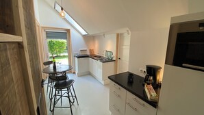 A modern kitchen with a dining area, a coffee machine, and a view of the outdoors.