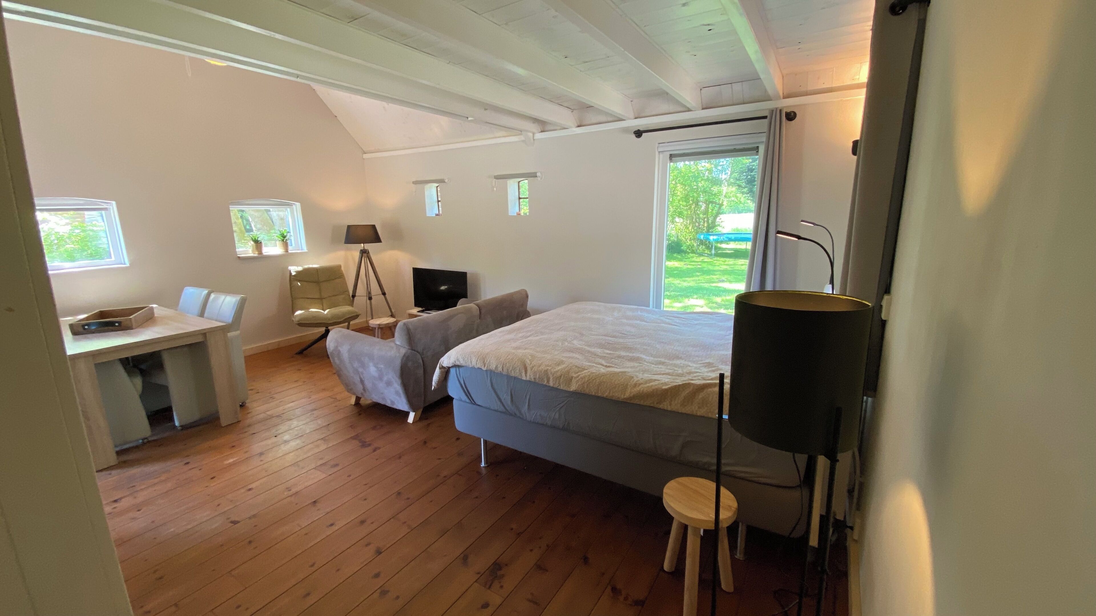 Ein Schlafzimmer mit einem Bett, einem Schreibtisch, einem Stuhl, einem Fernseher und einer Lampe.