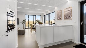 Une cuisine moderne dotée d’un grand îlot central, d’un coin repas offrant une vue agréable et d’œuvres d’art accrochées aux murs.