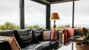 Una sala de estar moderna con un sofá de cuero negro, una mesa de centro de vidrio y vista al mar.