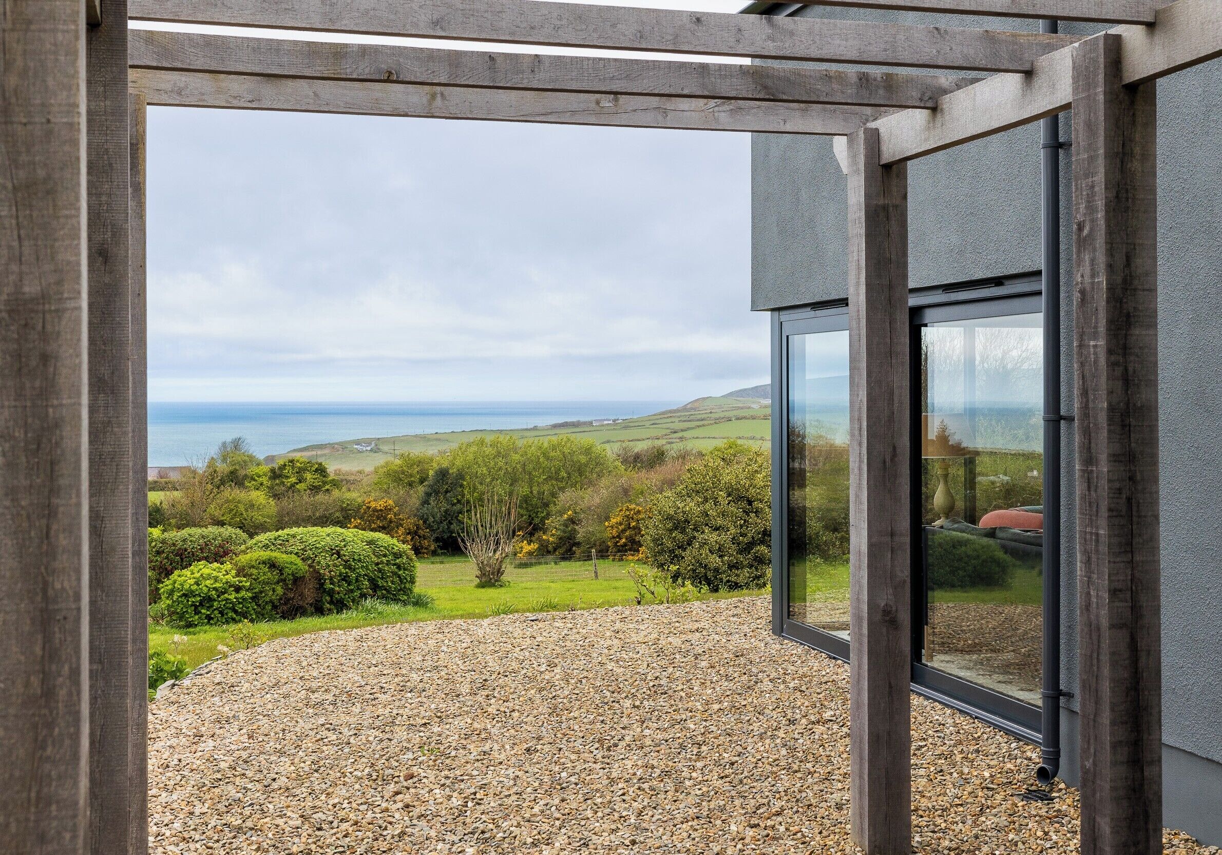 A modern building with a large glass window and a gravel patio.