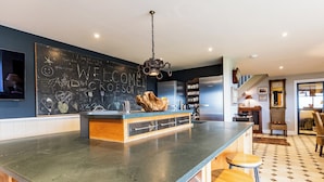 Una cocina moderna con pared de pizarra, taburetes de bar y electrodomésticos de acero inoxidable.