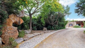 Un sendero de piedra que lleva a un edificio rústico con fachada de piedra y una ventana pequeña.
