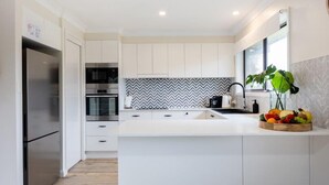 Eine moderne Küche mit weißen Schränken, einem Edelstahl-Kühlschrank, einem eingebauten Ofen und einer Rückwand mit Fischgrätmuster.
