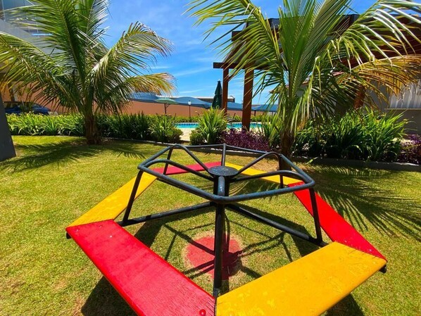 Une aire de jeux avec une balançoire colorée et des palmiers.