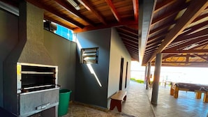 An outdoor patio area with a stone floor, a barbecue grill, a small bench, and a pool table. - Hotel Imigrantes LTDA (São Pedro)