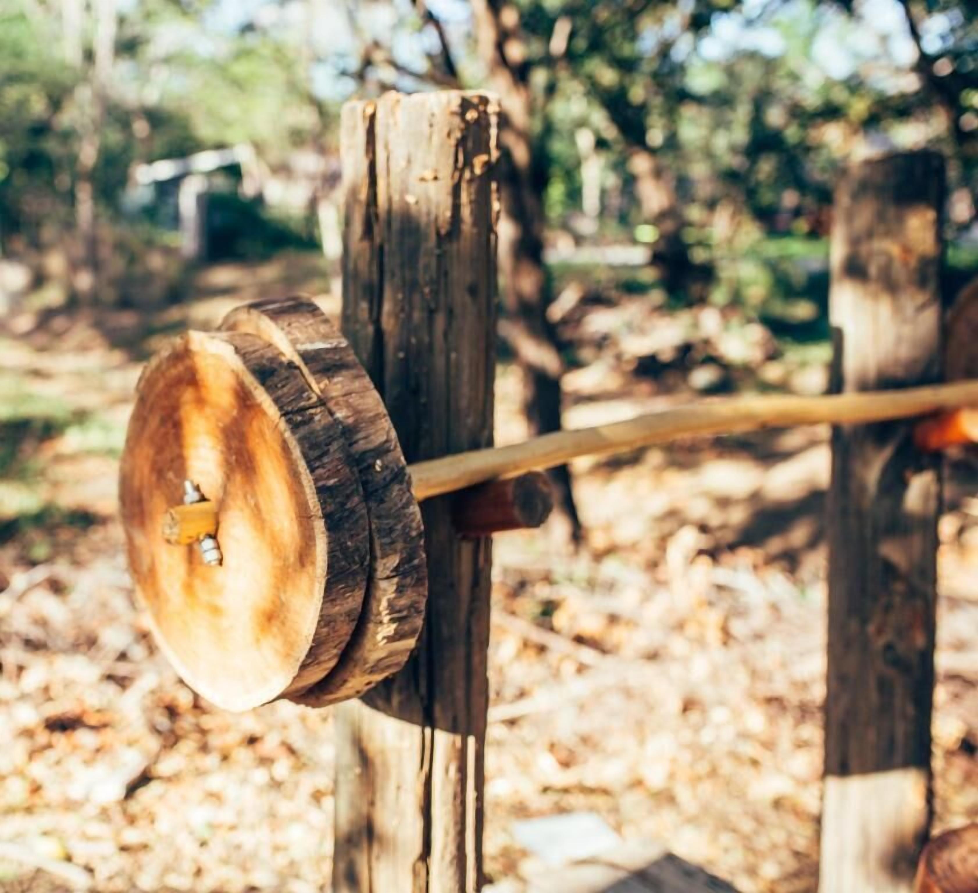 Una rueda de madera unida a un poste en una zona boscosa.