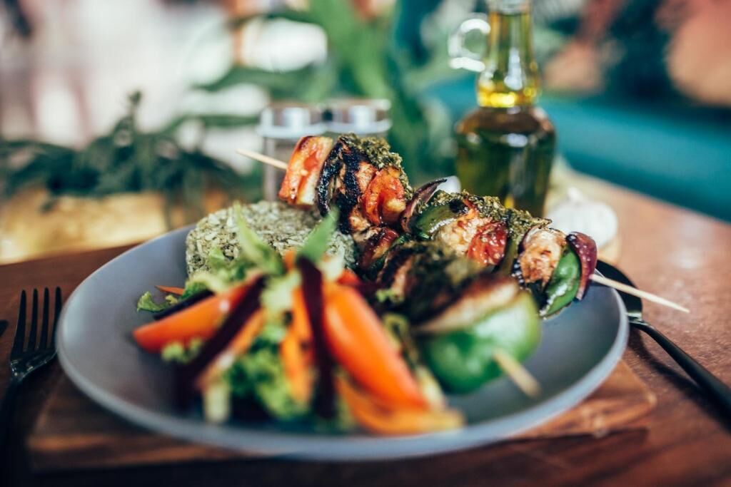 Une assiette de légumes grillés et de brochettes sur une table.