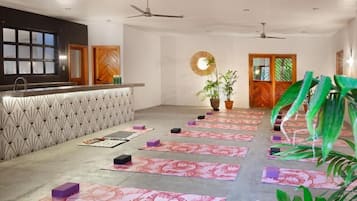 Un estudio de yoga con un espejo central, un mostrador de recepción y plantas en macetas.
