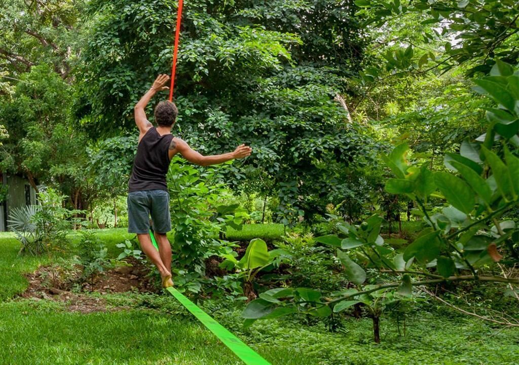 Une personne effectuant une routine de trapèze aérien dans un jardin luxuriant et verdoyant.