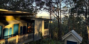 A treehouse with a balcony and a small attached structure, surrounded by dense forest. - Heaven in the Hills (Reesville)