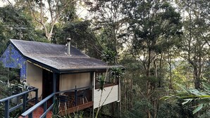 Une petite cabane rustique, dotée d’un toit en pente, entourée d’une forêt dense.