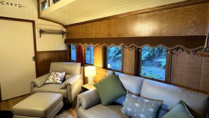 Une pièce confortable avec un canapé, un fauteuil et un pouf, une lampe et une fenêtre avec des rideaux.