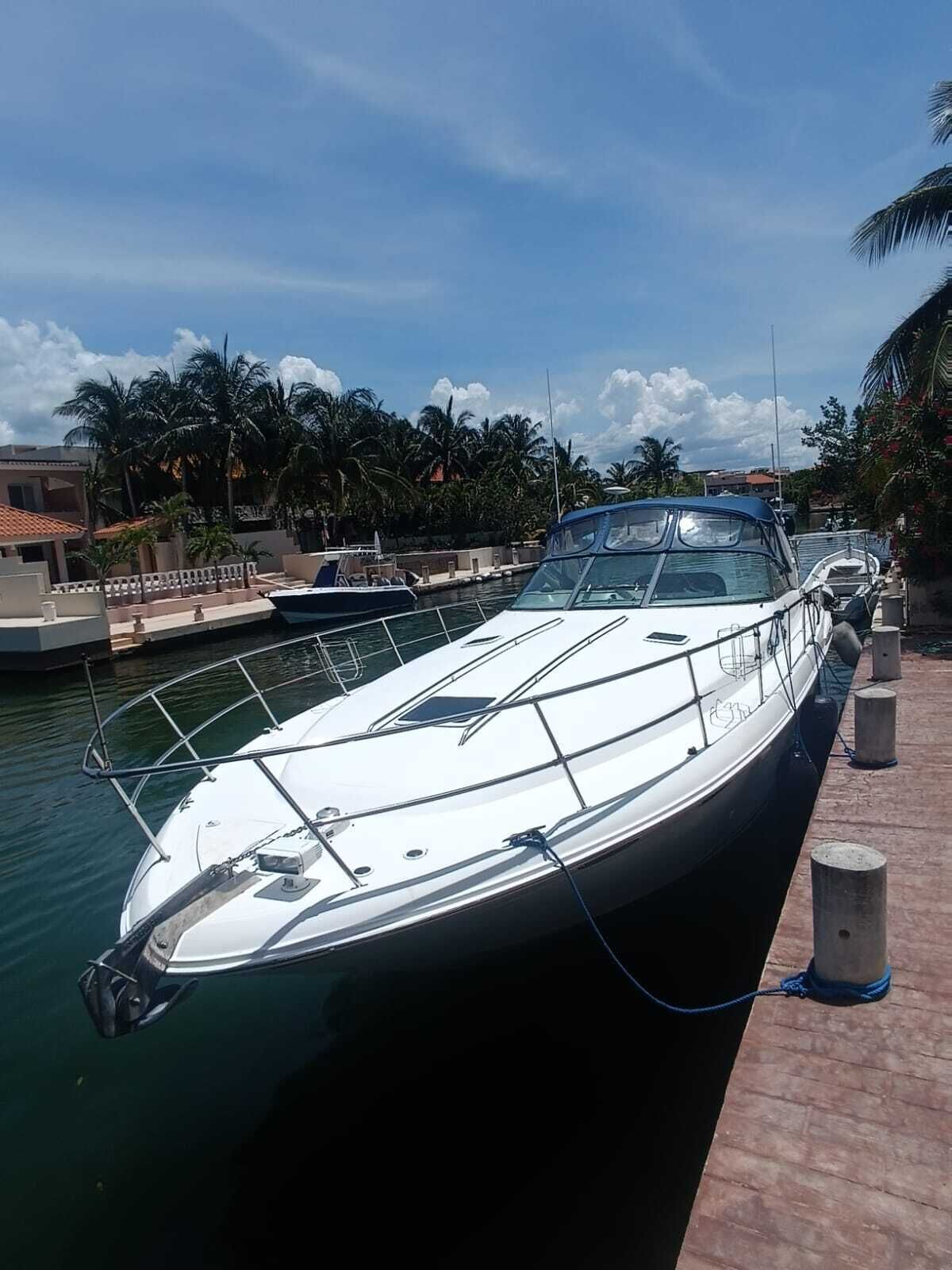 Un yacht blanc était amarré dans une marina, avec un ciel dégagé et des palmiers en arrière-plan.