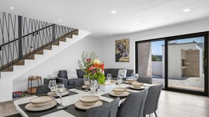 A modern dining area with a long table set for six, a staircase with a unique railing design, and a large window offering a view of the outdoors. - Stunning home in Vodice with WiFi (Vodice)