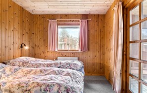 Relax in this serene bedroom with two beds, a window offering a view, and a radiator for warmth.