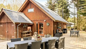 A wooden barn with a dining area featuring wicker chairs and a table. - 4 bedroom beautiful home in Thyholm (Thyholm)