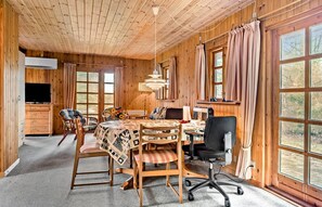 Cozy cabin-style interior with a dining area, seating area, and large windows offering views of the surrounding landscape.
