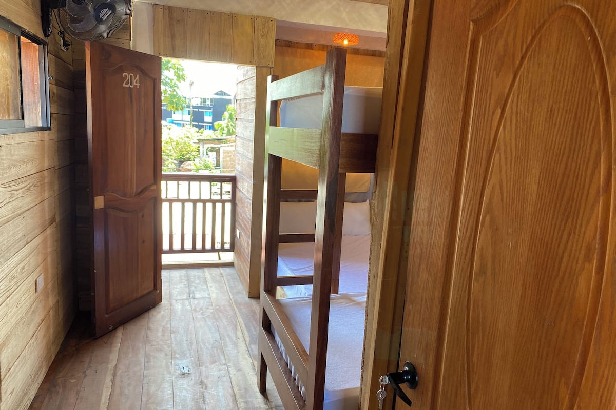 A wooden interior with a bunk bed, a door labeled '204', and a fan.