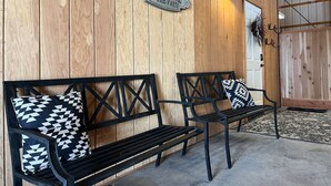 A barn interior with wooden walls, a welcome sign, and two black benches with patterned cushions.