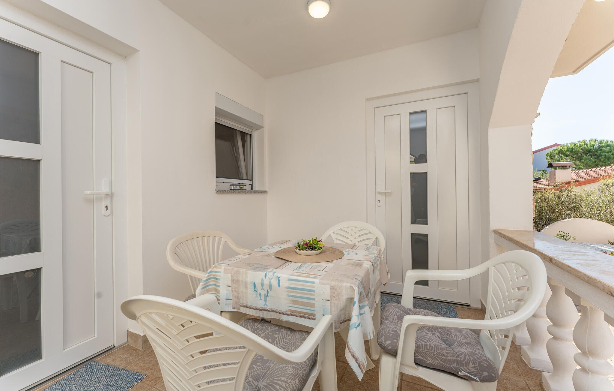 A small, enclosed patio area with a table and chairs, a small window, and a door.