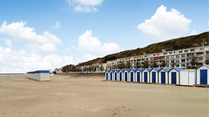 Ein Strand mit einer Reihe blauer und weißer Strandhäuser und Gebäuden im Hintergrund.