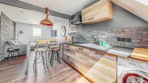 Eine moderne Küche mit Steinrückwand, Holzschränken und einer integrierten Waschmaschine.