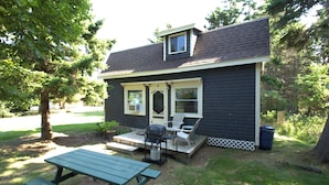 A house with a porch, a barbecue grill, and a picnic table.