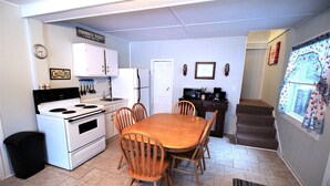A compact kitchen with a stove, refrigerator, and dining table with chairs.
